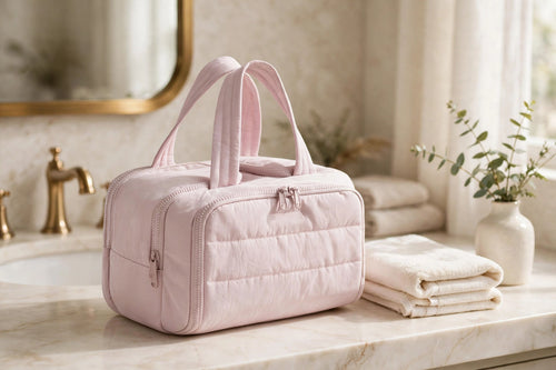 CloudPuff Wide-Open Travel Toiletry and Makeup Bag in Pink on an ivory bathroom vanity